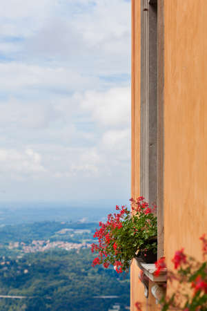 Flowers on the window against view of city in mountiains, Italyの写真素材
