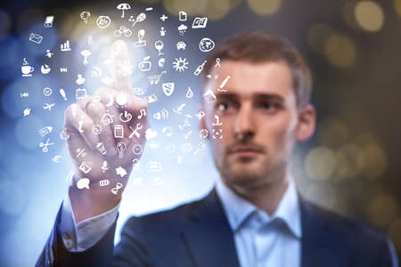 business man pressing touchscreen button with set of icons in airの写真素材