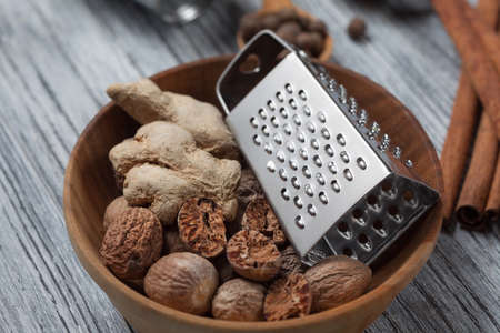 Ginger with nutmeg and grater in bowl on wooden backgroundの写真素材