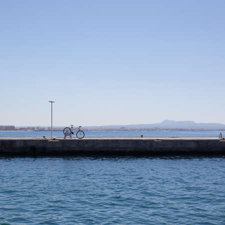 Bike on pier against sea and blue skyの写真素材