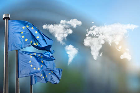 Flags of European Union with world map made of clouds against European Parliament in Brussels, Belgiumの写真素材