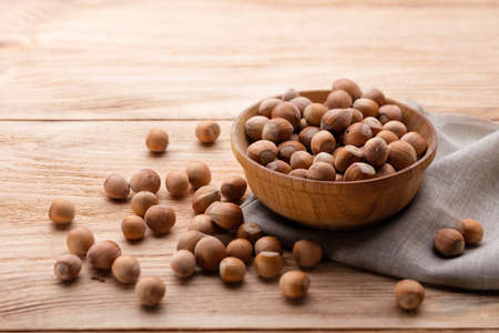 Hazelnuts in bowl on wooden tableの写真素材