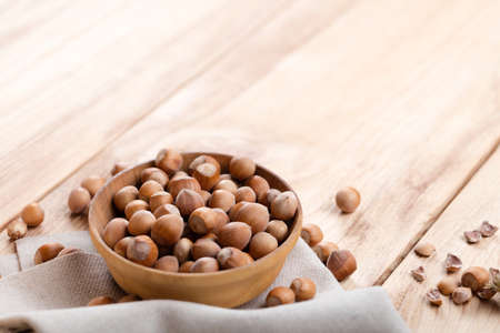 Hazelnuts in bowl on wooden tableの写真素材