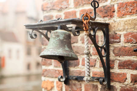 Old iron bell hanging on brick wallの写真素材