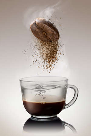 Ground coffee from bean falling into cup with hot waterの写真素材