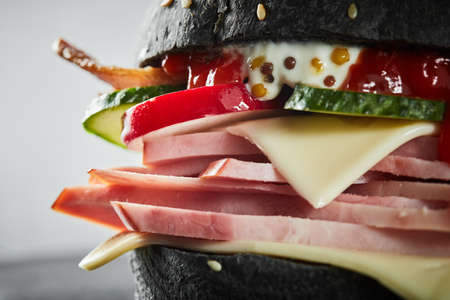 Burger with ham and black bun, with lettuce and mayonnaise and ketchup on white background. Macroの写真素材