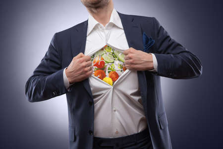 man in suit with salad inside isolated on dark. Natural healthy food conceptの写真素材