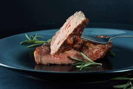 Succulent thick grilled beef steak trimmed for fat for a healthy diet on a griddle with a sprig of fresh rosemaryの写真素材