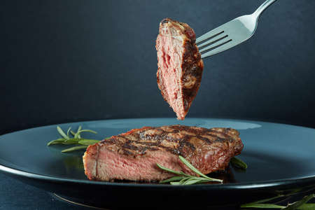 Juicy steak medium rare beef with spices and a piece of meat on a forkの写真素材