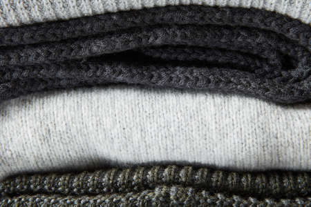 Stack of grey knitted clothes close up