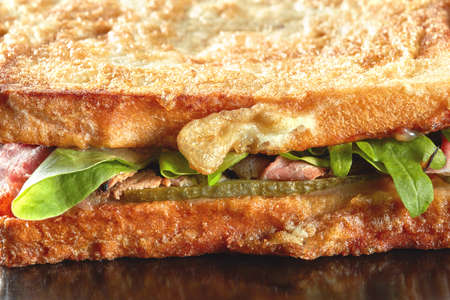 macro sandwich with cucumber,salad, ham and eggs on the black plateの写真素材