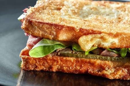 sandwich with ham and green salad grill on the black plateの写真素材