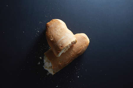 Italian bread in half the broken isolated on blackの写真素材
