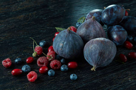 Fresh figs of different varieties berries on a dark wood table
