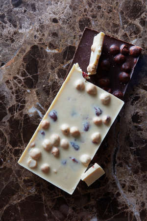 dark and white chocolate with nuts on a marble dark background
