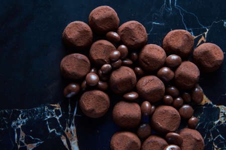 Homemade chocolate truffles on a black marble background.