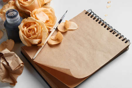 Closeup of diary or notebook covered by orange roses and their flowers for your notes. Ink pen is...