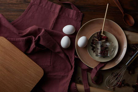 Kitchen utensils with chicken eggs on a wooden dark background, flat layの写真素材