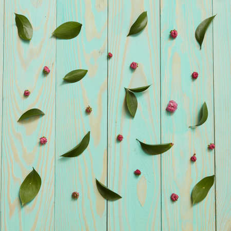 Blue wooden background decorated with leaves and flowers flat lay