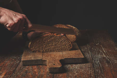 Hands cutting rye breadの写真素材