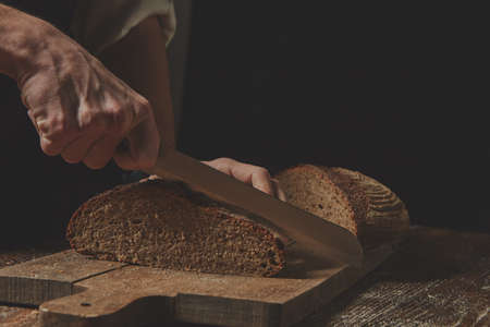 Hands cutting rye breadの写真素材