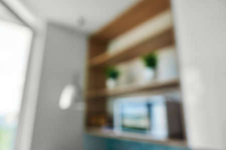 Natural lens bokeh.Blurred view of kitchen interior with shelves, vases and microwave near the windowの写真素材