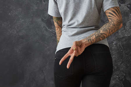 Girl shows a sign of victory behind her backの写真素材