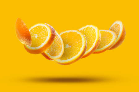 flying pieces of a slice of ripe orange isolated on an orange background