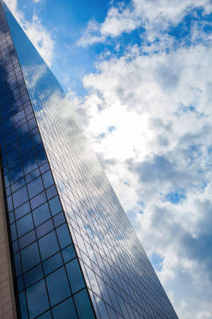 clouds reflection on highrise glass building against sky