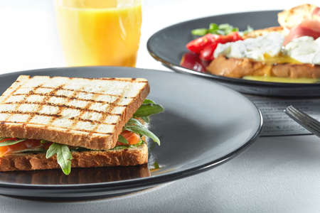 Grilled BLT Bacon, Lettuce and Tomato Sandwiches with Chicken and orange juice on a white tableの写真素材