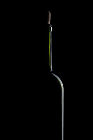 silhouette of bottle with wine on black background close-upの写真素材