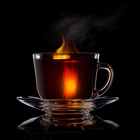 glass cup with tea and saucer isolated on black background close-upの写真素材