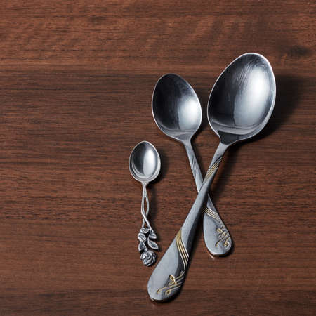 three different metal spoons on a brown wooden table flat layの写真素材