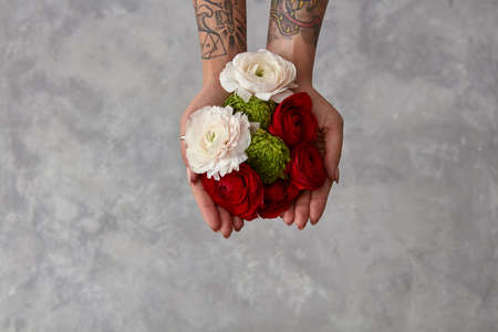 girl with a tattoo on her hands holding a bouquet of flowers