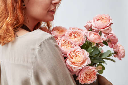 Woman holding a vase with fresh pink roses