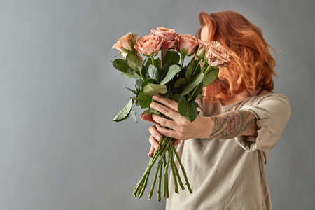 Red-haired girl gives a beige roses cappuccino