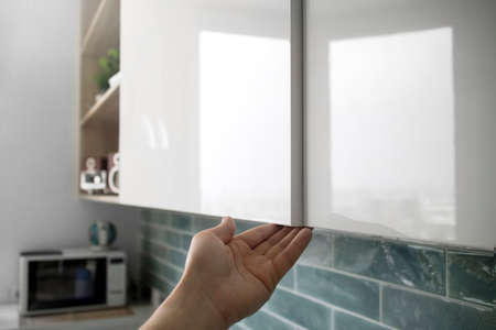 male hand open the cupboard doors in the kitchen