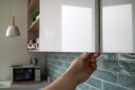 kitchen cabinet with doors without handles, the mans hand shows how the doors open without handlesの写真素材