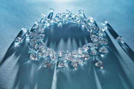 Shiny ice cubes in the form of a round frame on a blue background