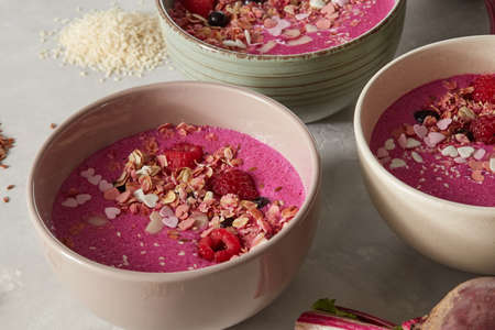 Healthy breakfast red smoothie bowls topped with fruits, nuts and berries
