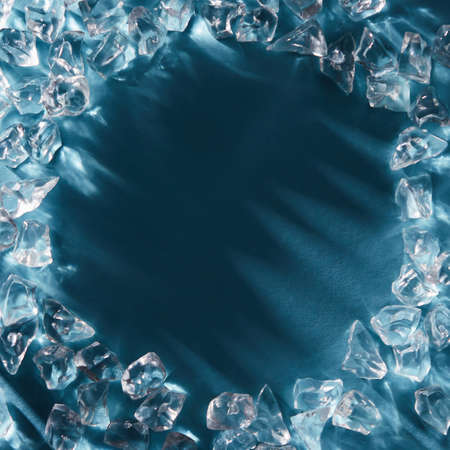 Close-up of crystals of ice cubes in the form of a frame on a blue blue background. Flat layの写真素材