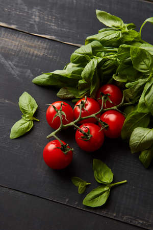 Tomatoes and basil leaves on wooden tableの写真素材