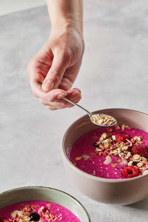 Preparing breakfast, the girls hand puts oatmeal in a fruit smoothie Preparing breakfast, the girls hand puts oatmeal in a fruit smoothie