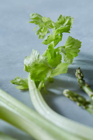 Close-up of fresh celery and asparagus on a gray concrete background