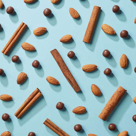 Pattern of almonds, cinnamon and chocolate balls on a blue paper background flat layの写真素材