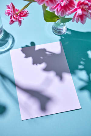A bouquet of tulips in a vase and a cardboard with copy space on a blue background.