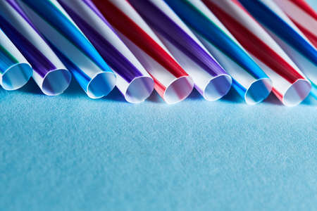 Blue, purple and red plastic straws on a blue paper background. Copy space for textの写真素材