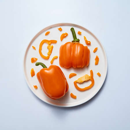 yellow peppers slice and half on white plate isolated on grayの写真素材