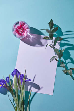 bouquet of irises on a blue background with a glass vase and a white paper, top viewの写真素材