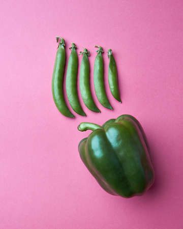 green pea pods and green sweet pepper on a pink background
